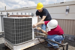 Commercial HVAC service staff repairing a central air unit on a commercial property.